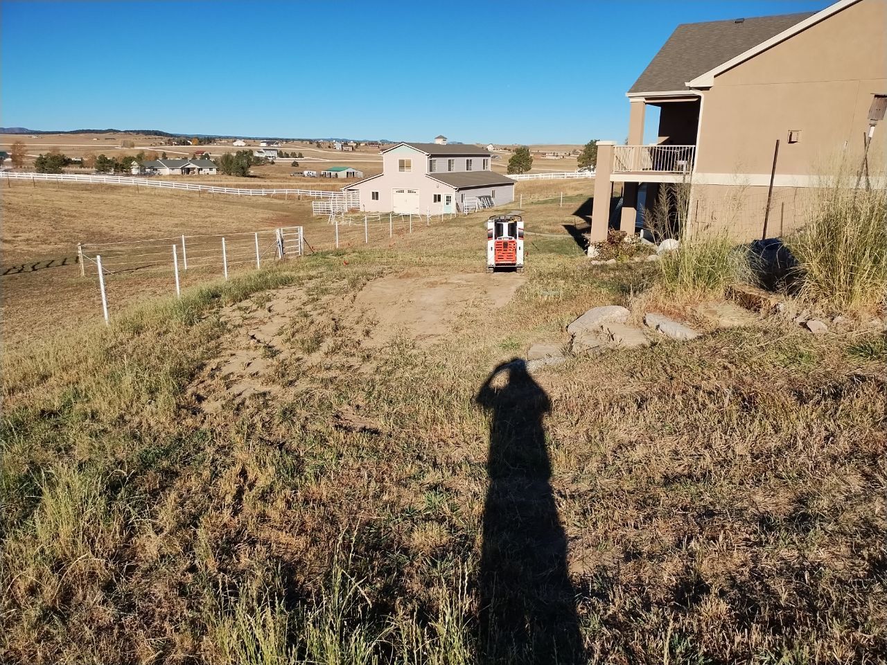 A shadow of a person is cast on the ground in front of a house