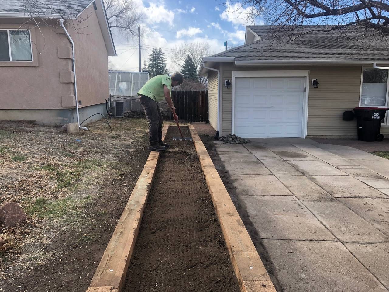 A man is digging a path in front of a house