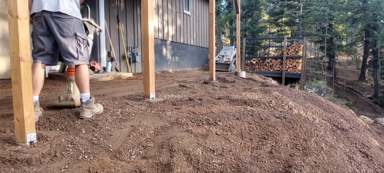 A man is standing on a pile of mulch in front of a house.