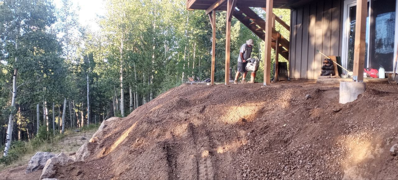 A pile of dirt is in front of a house under construction.
