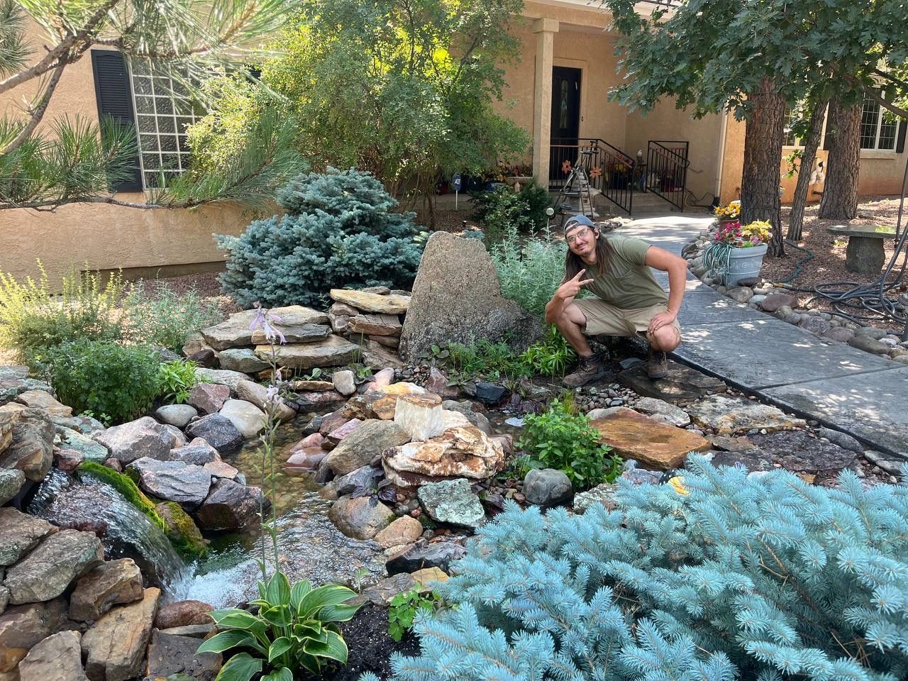A man is kneeling in a garden in front of a house.