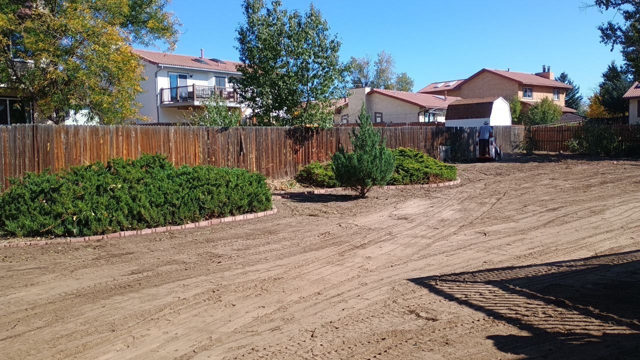 A dirt yard with a wooden fence in the background