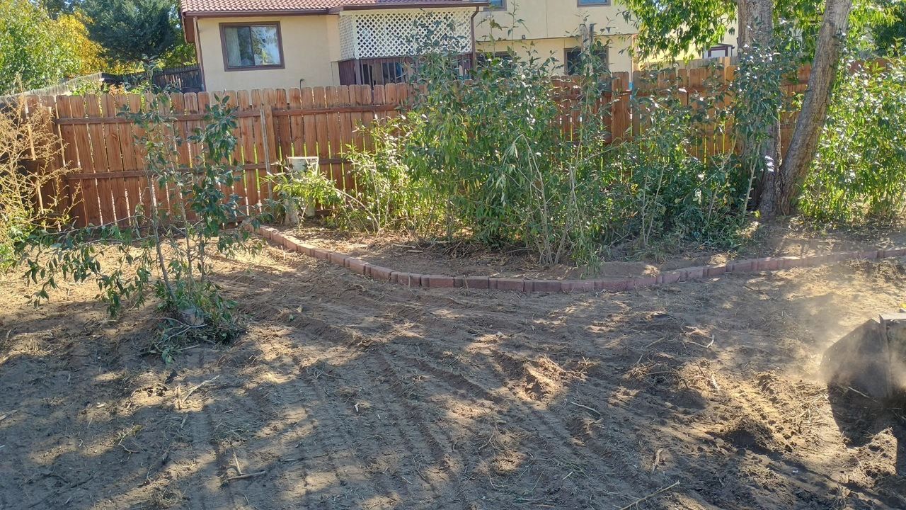 A person is digging in the dirt in front of a house