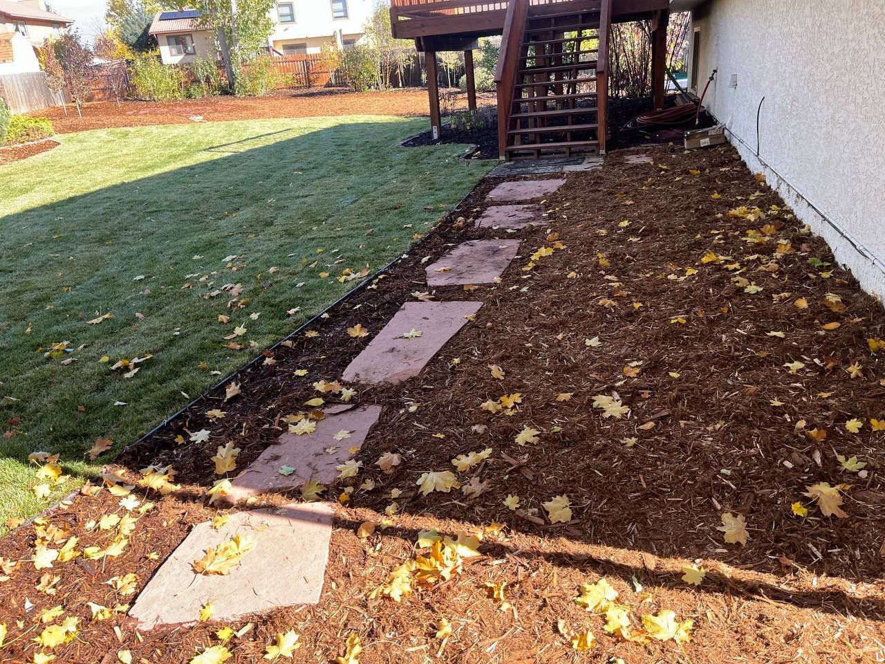 A stone walkway leading to a deck in a backyard