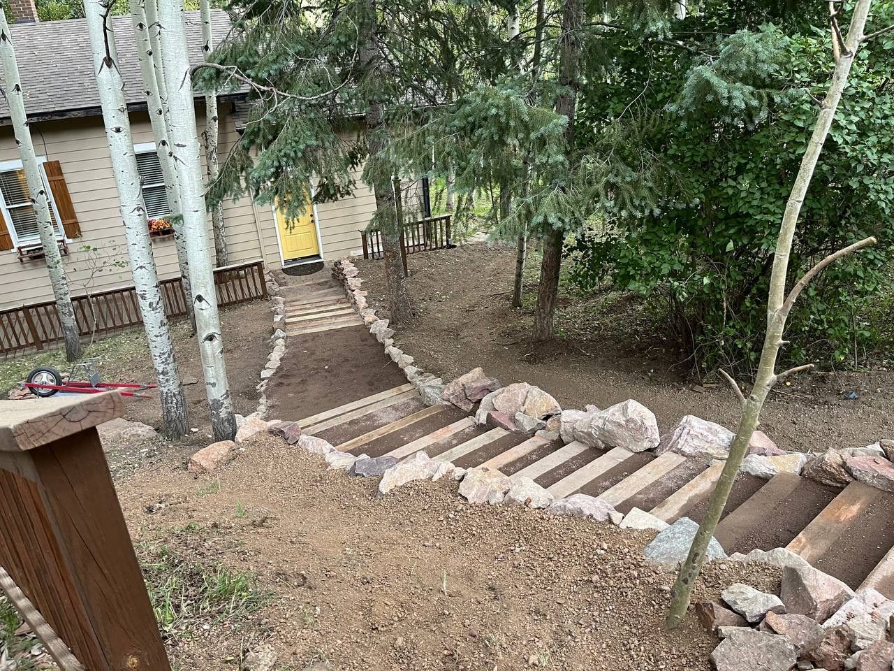 A wooden staircase leading up to a house in the woods.