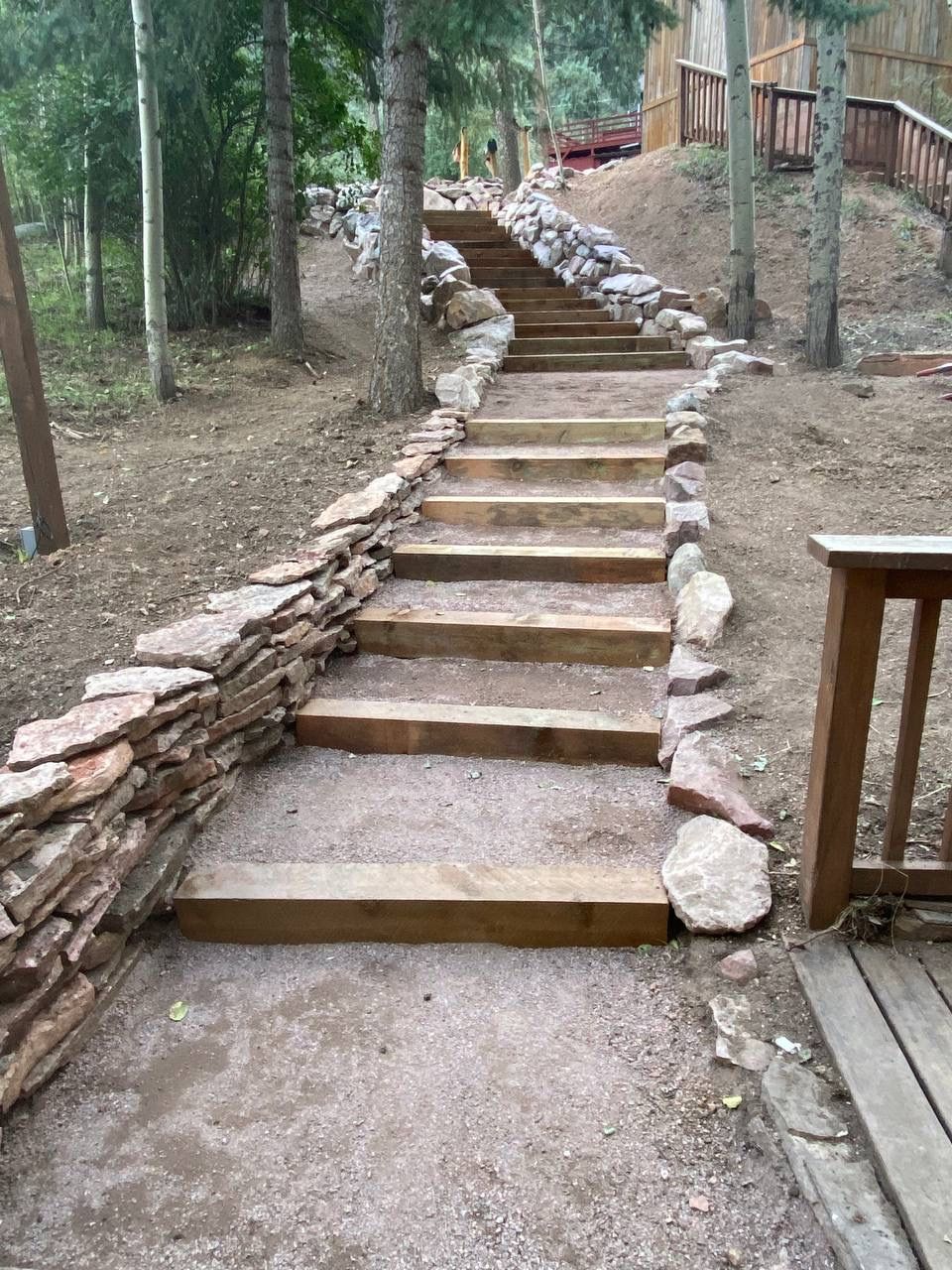 A set of wooden stairs leading up to a stone wall