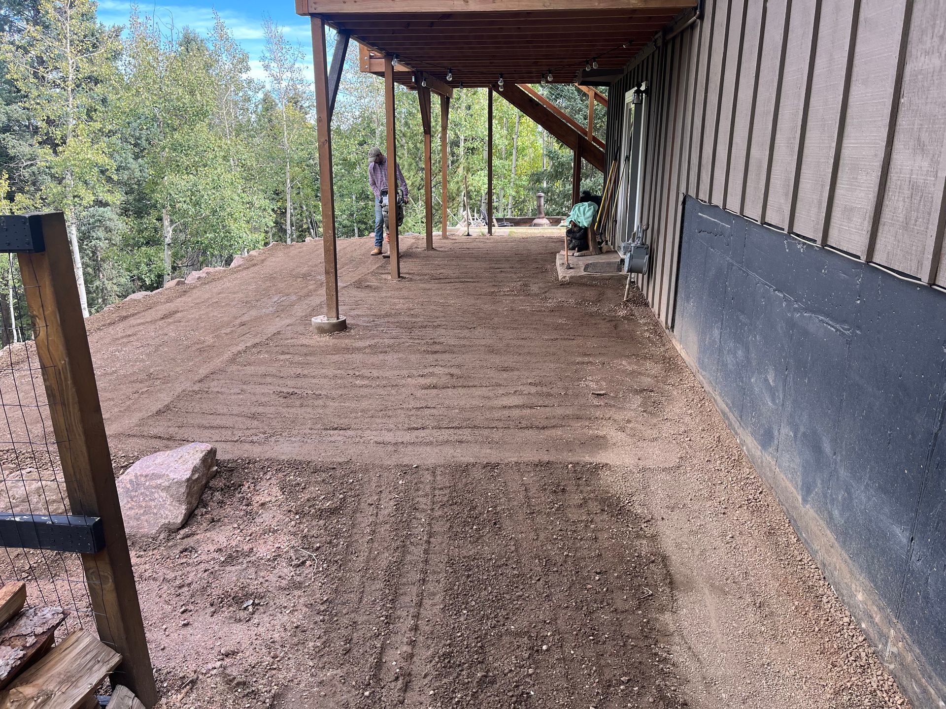 A man is standing on a dirt path next to a house.
