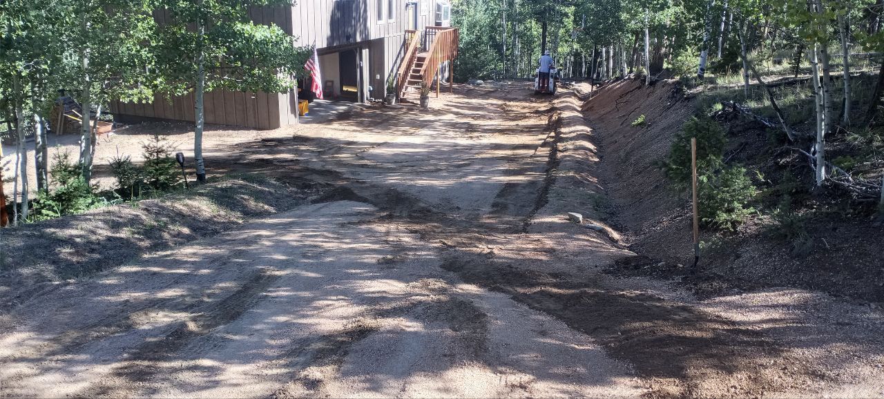 A dirt road with a house in the background