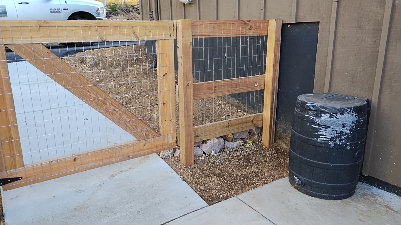 A wooden fence with a black barrel in front of it
