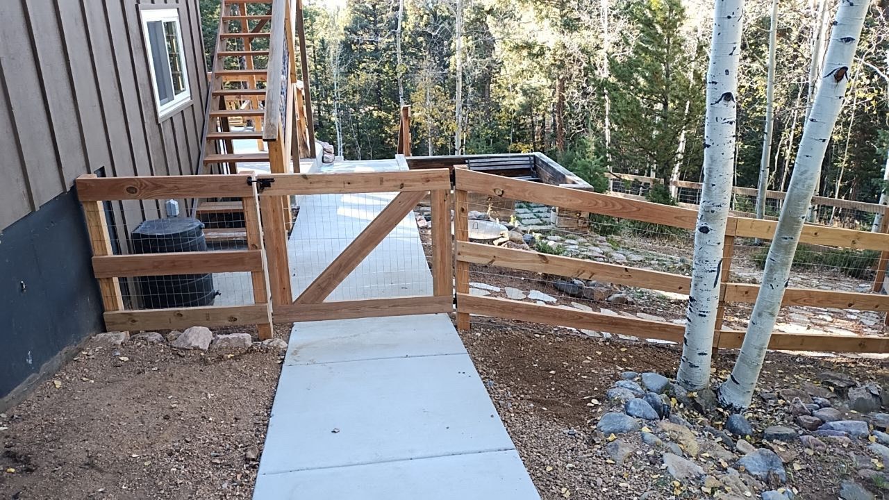 A wooden fence surrounds a walkway leading to a house
