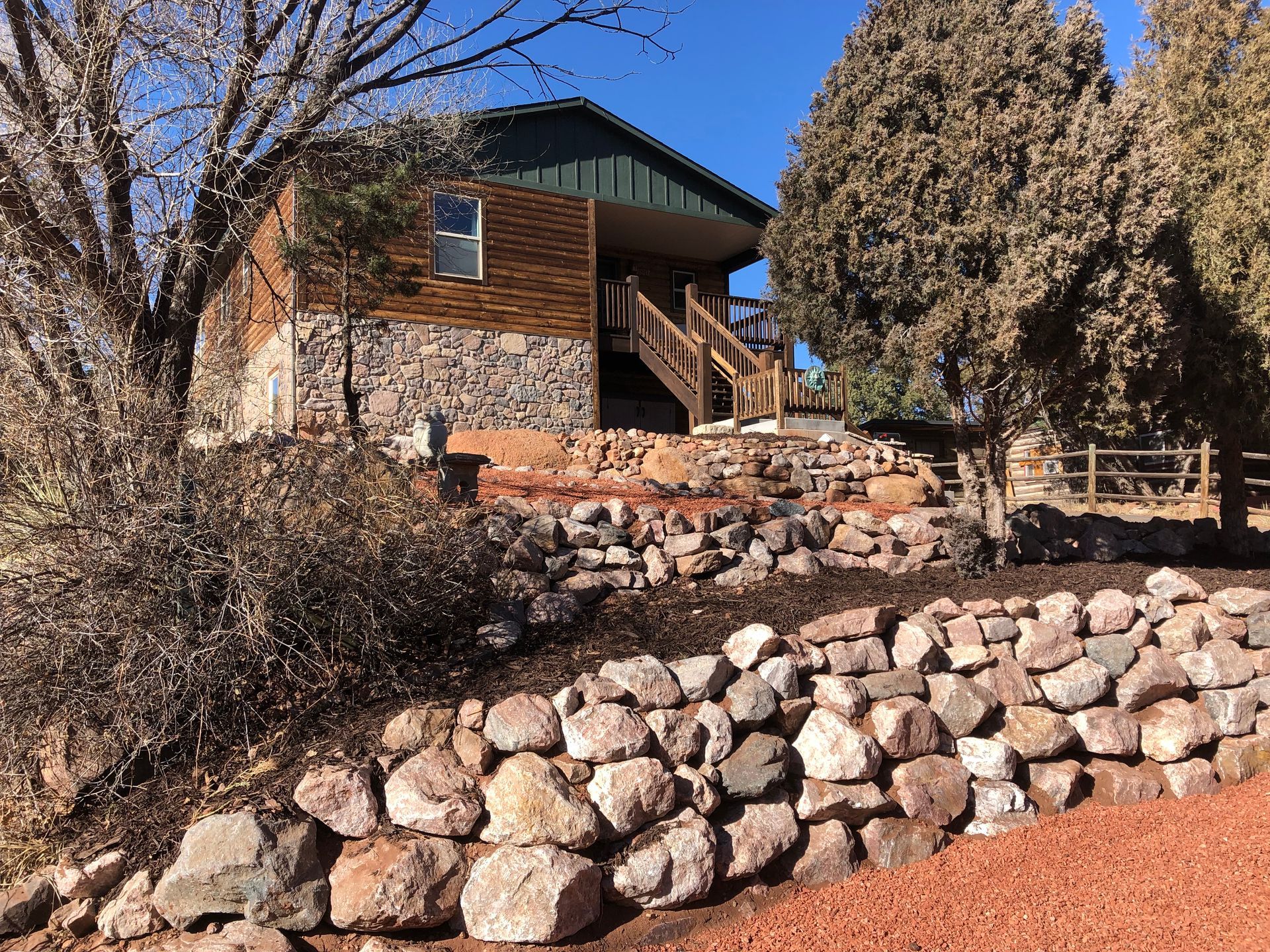 A house with stairs leading up to it is surrounded by rocks and trees