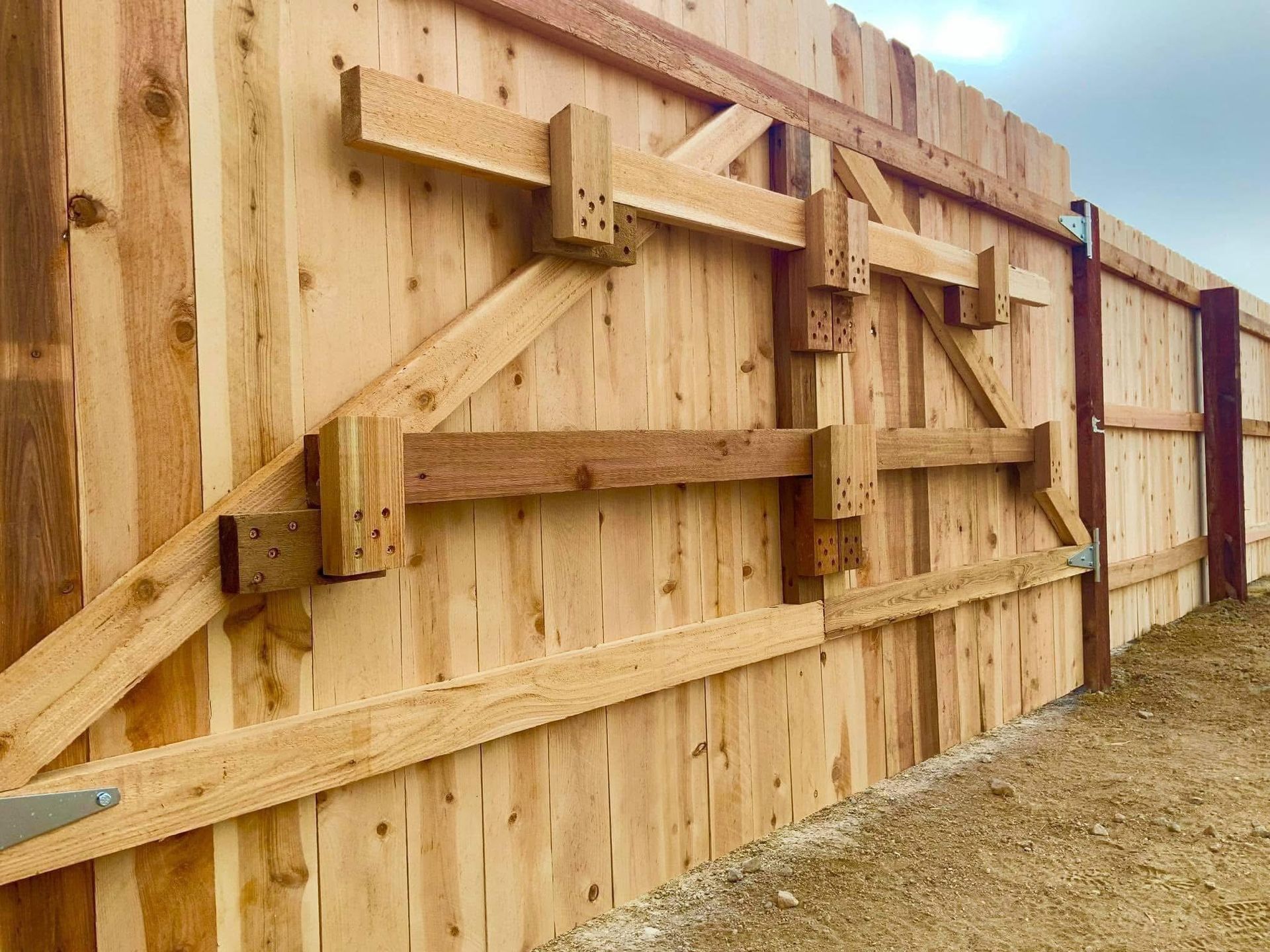 A wooden fence is being built on a dirt road