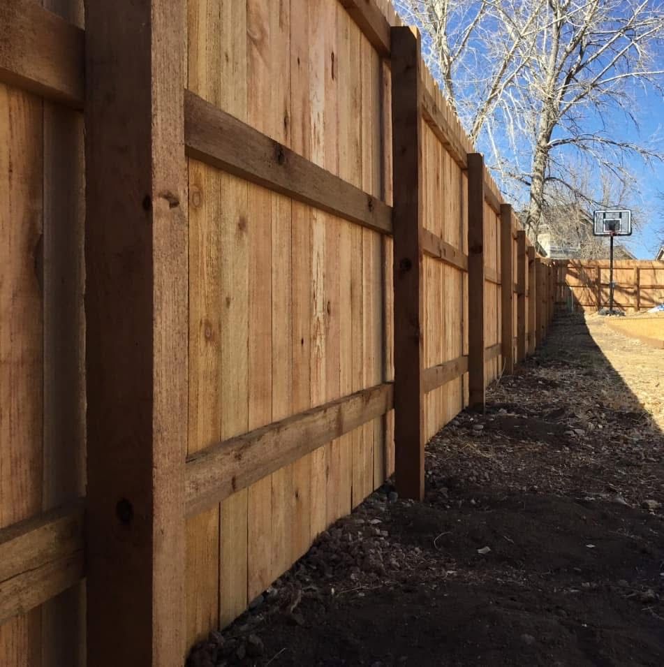 A wooden fence with a basketball hoop in the background