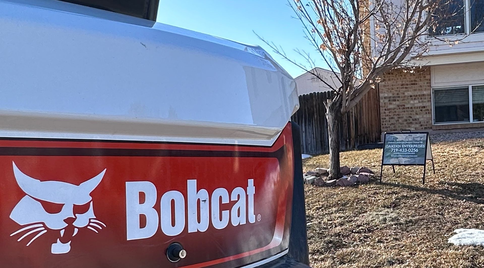 A bobcat vehicle is parked in front of a house