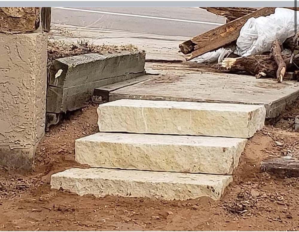 Stone steps under construction next to a pillar and debris.