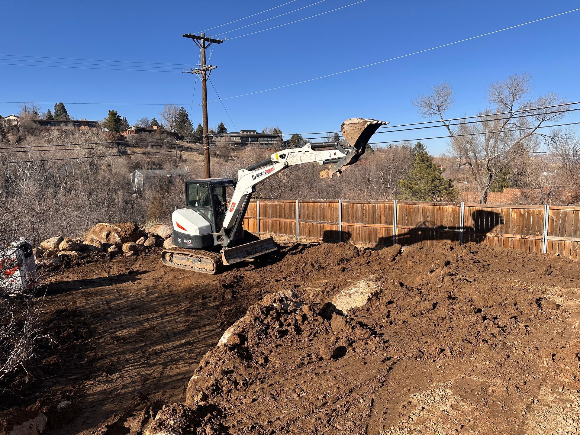 A bobcat excavator is moving dirt in a backyard