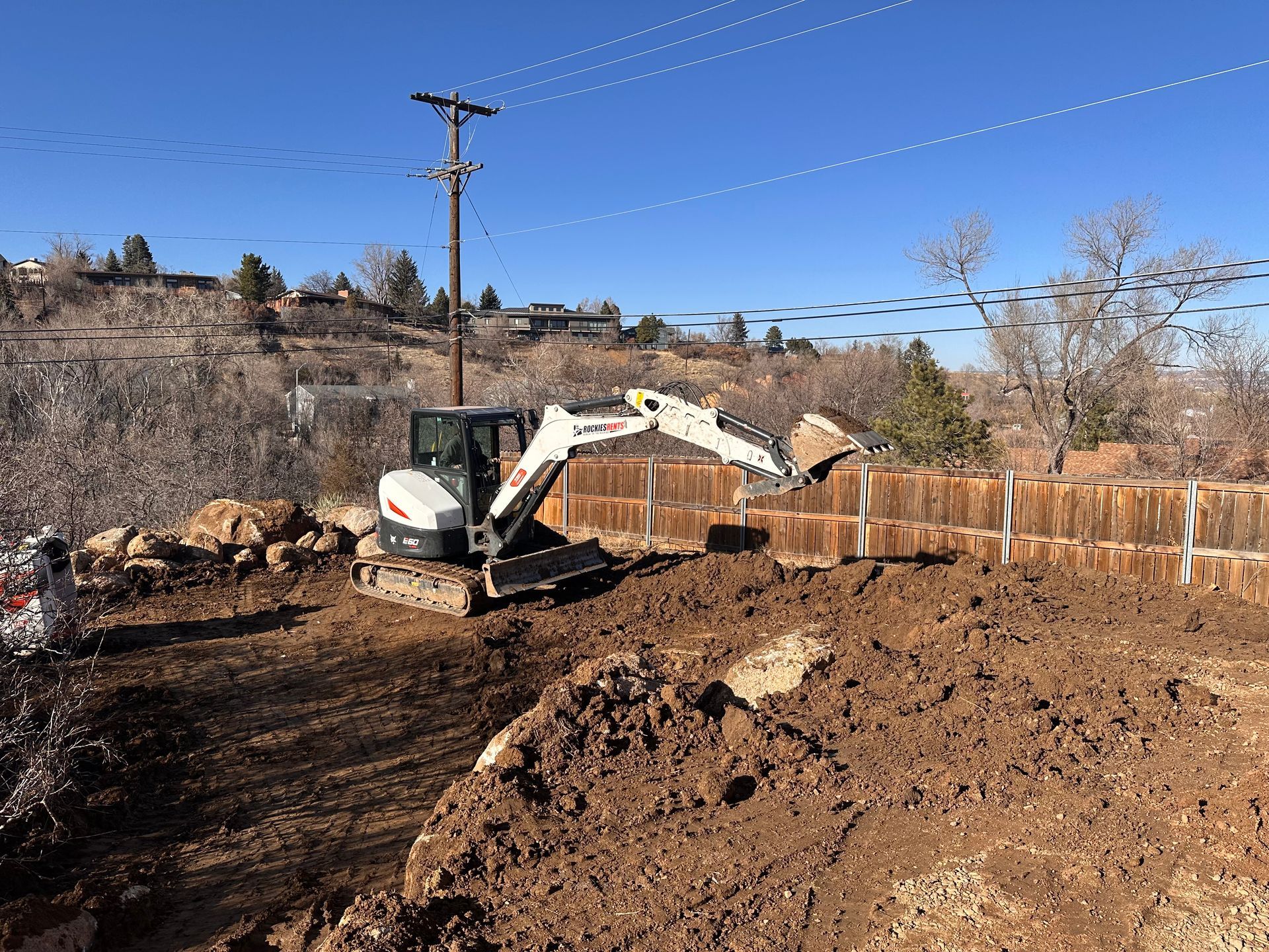A bobcat excavator is digging a hole in a dirt field