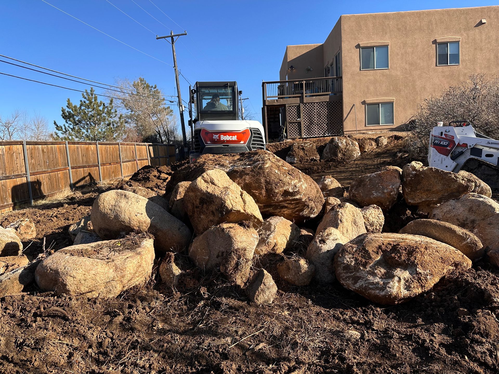 A bobcat excavator sits on top of a pile of rocks