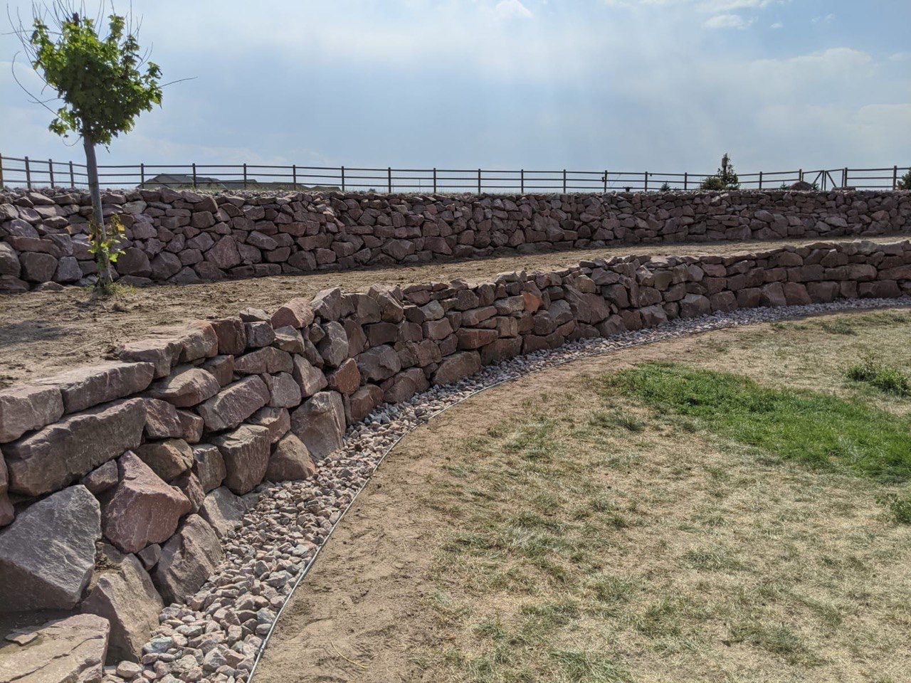 A stone wall surrounds a lush green field