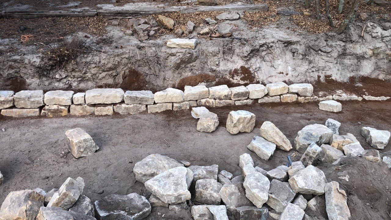 A pile of rocks on the ground with a brick wall in the background