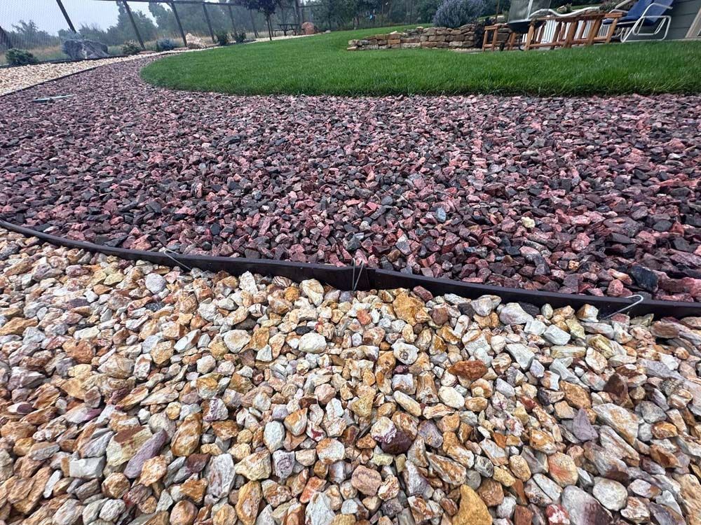 Gravel pathway with brown and tan stones, bordered by a black edging, leading to a green lawn.