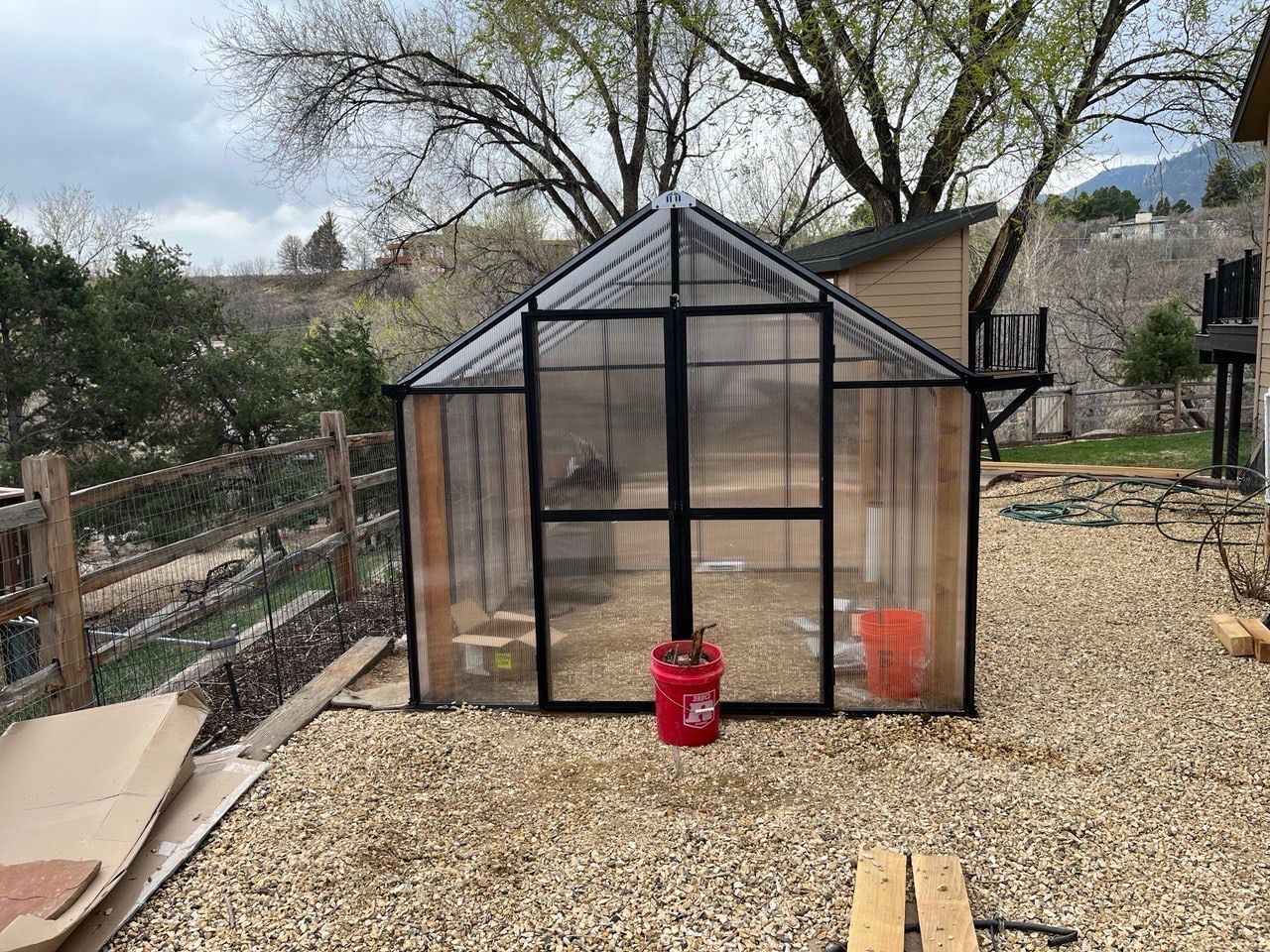 A greenhouse with a red bucket in front of it