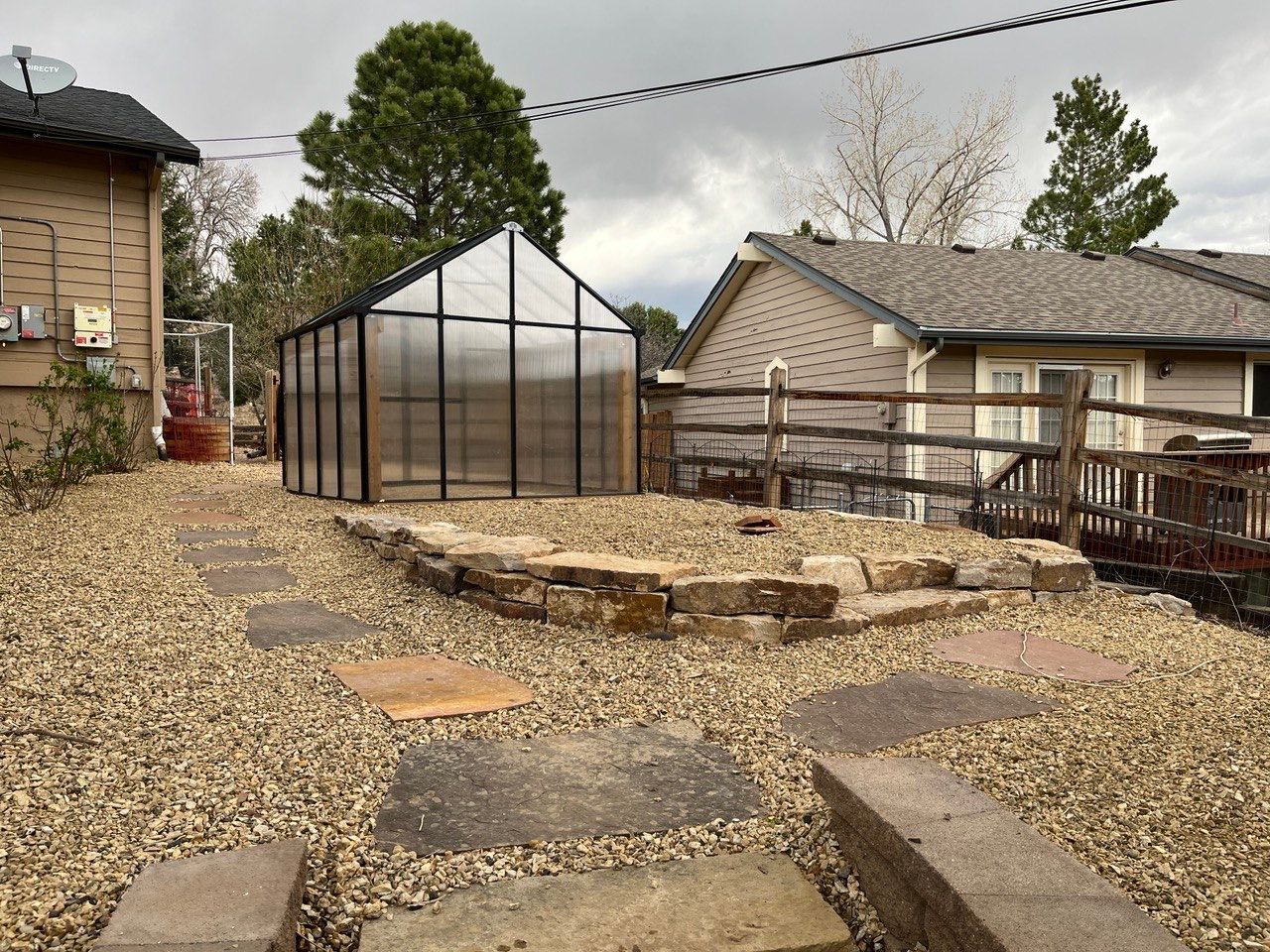 A greenhouse is in the backyard of a house