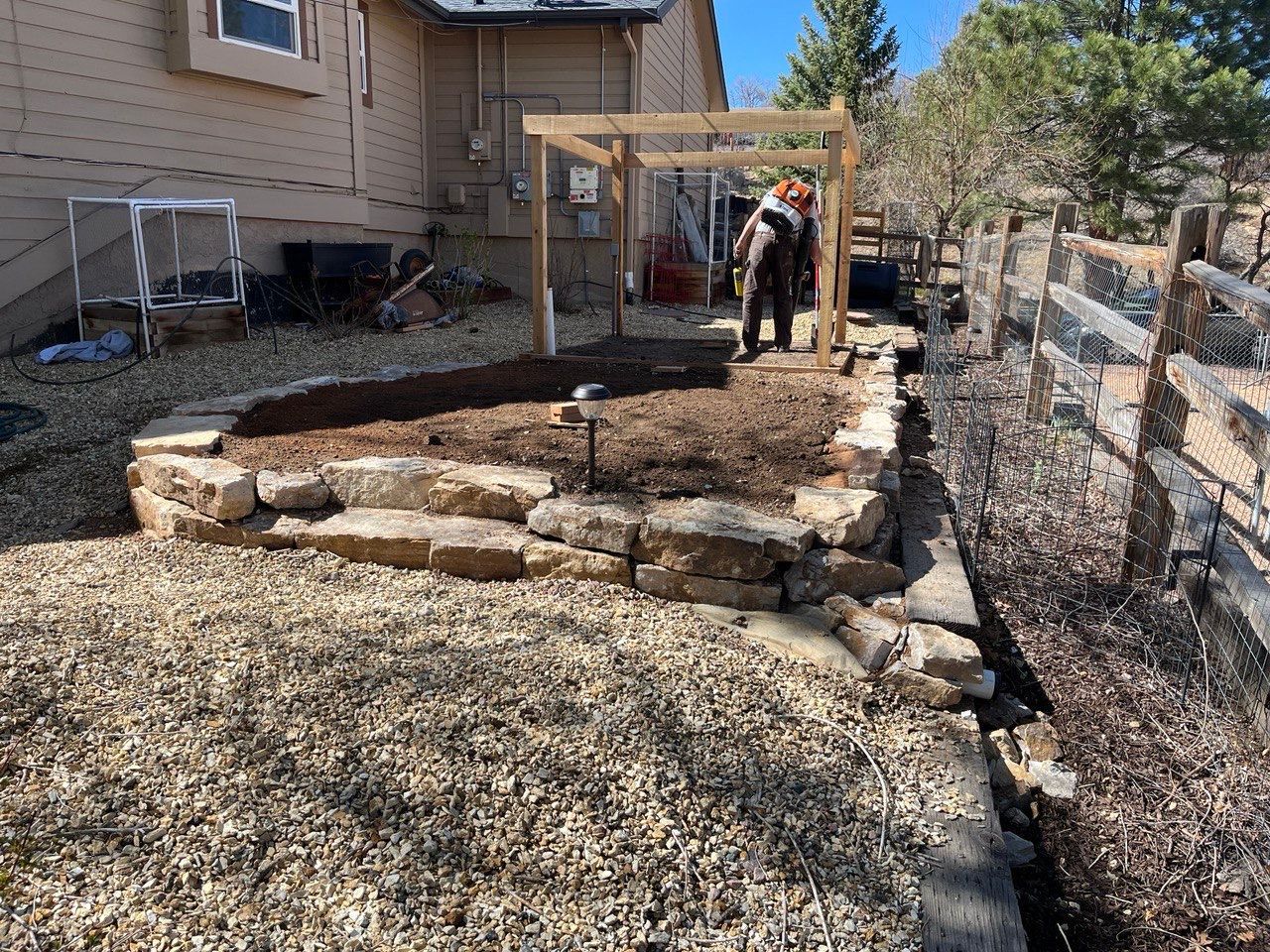 A man is standing in the dirt in front of a house.