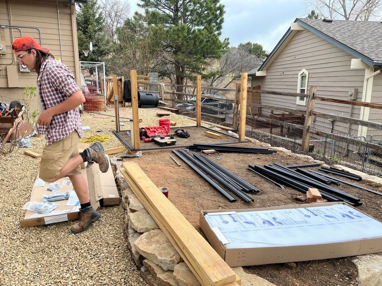 A man in a plaid shirt is working on a fence