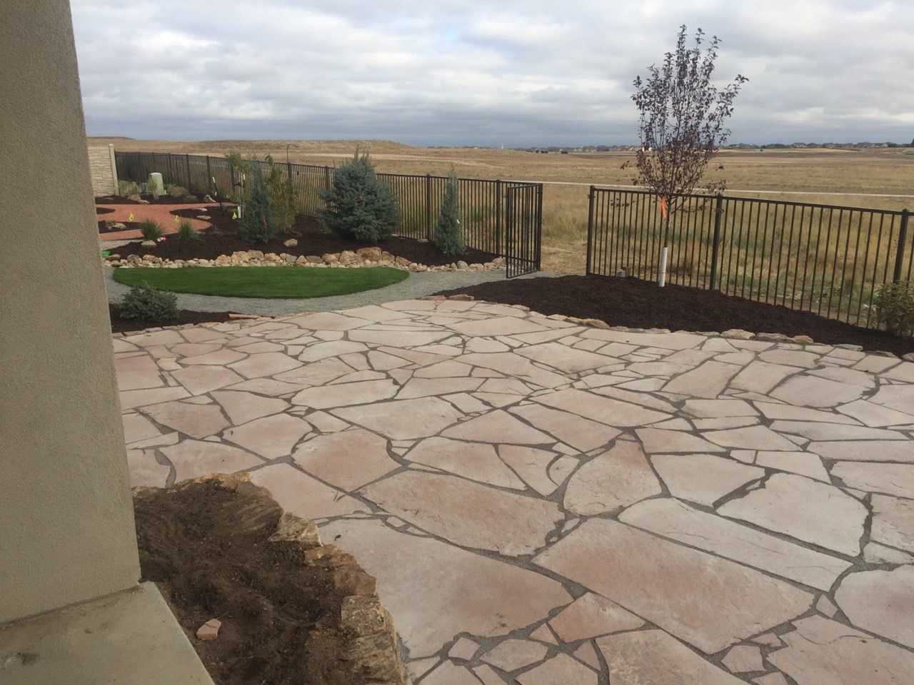 A stone patio with a fence in the background