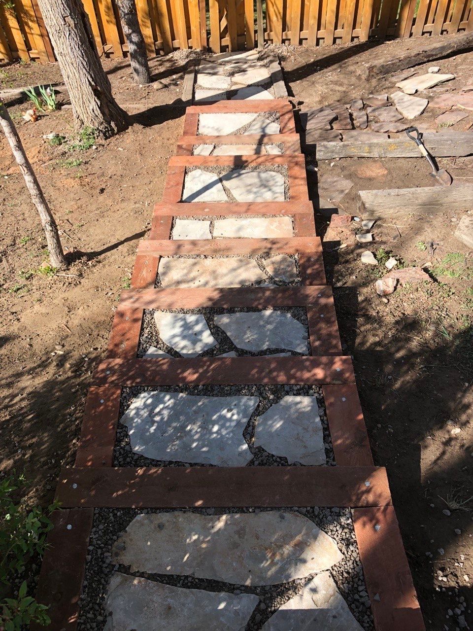 A stone walkway with a wooden fence in the background