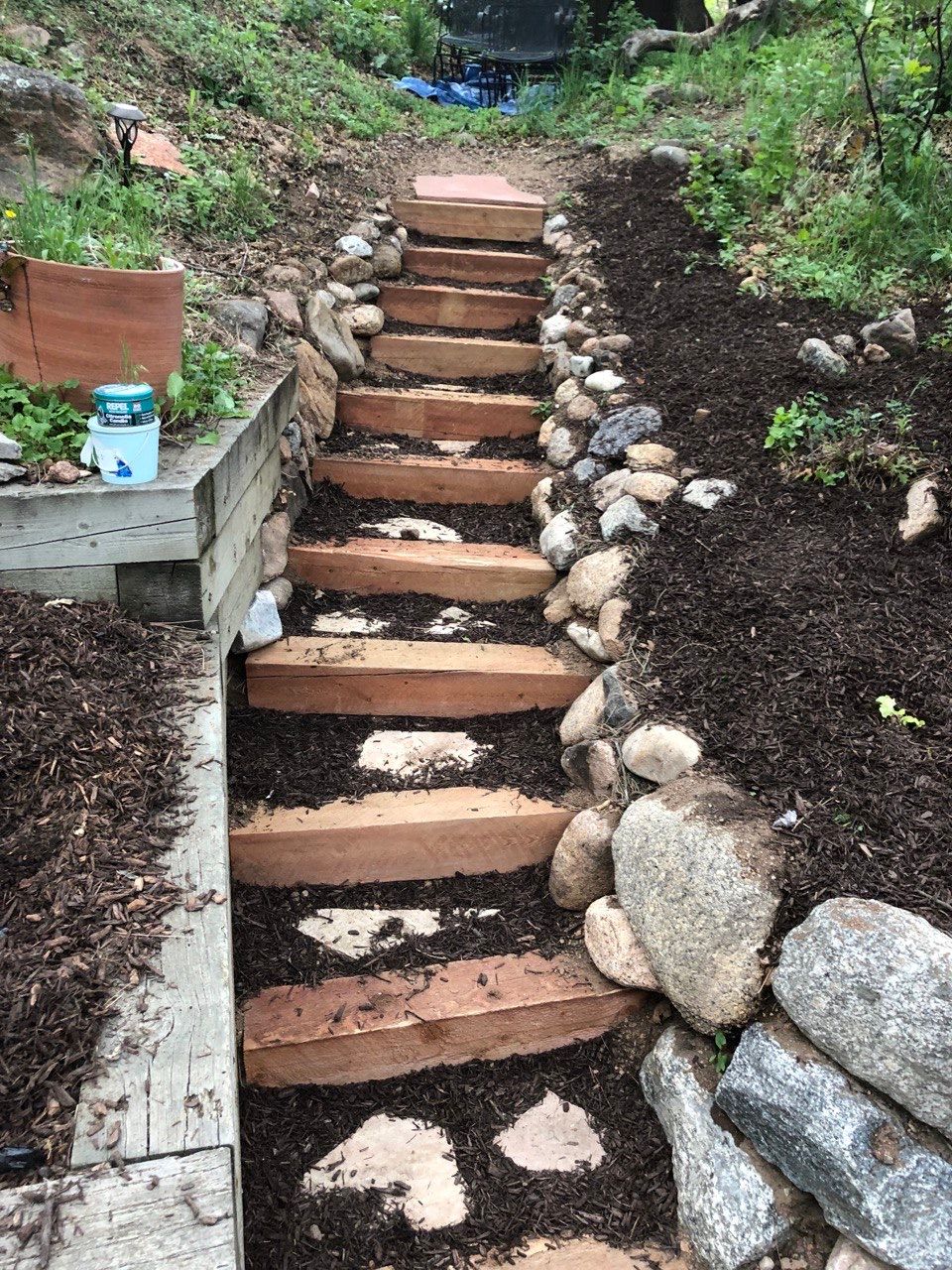 A set of wooden stairs going up a hill in a garden.