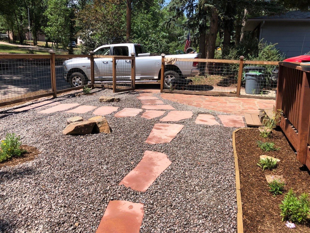 A silver truck is parked in a gravel yard