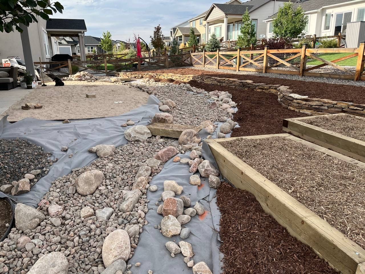 A pile of rocks and gravel in a yard with a fence in the background.