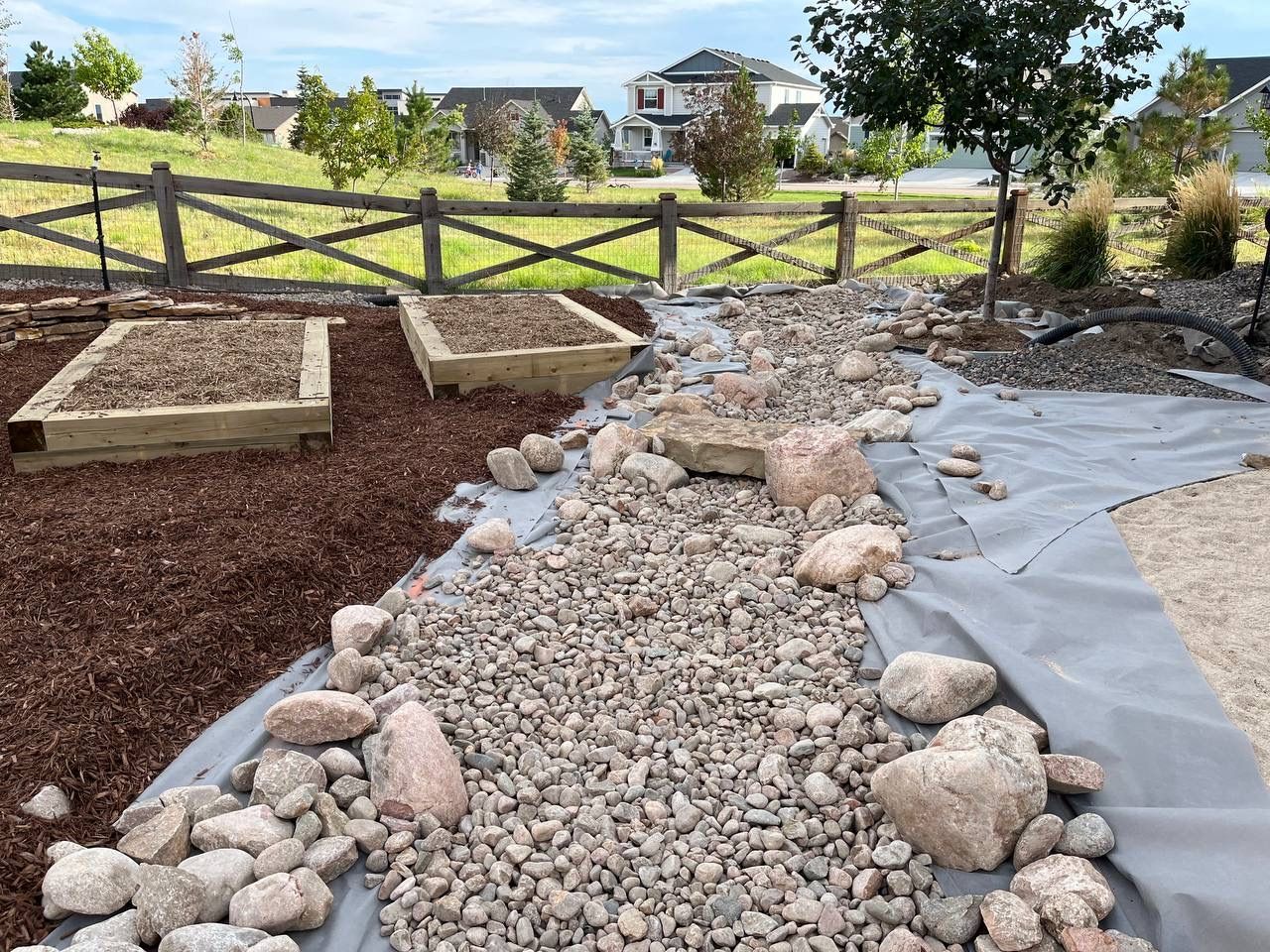 A gravel path with a wooden fence in the background