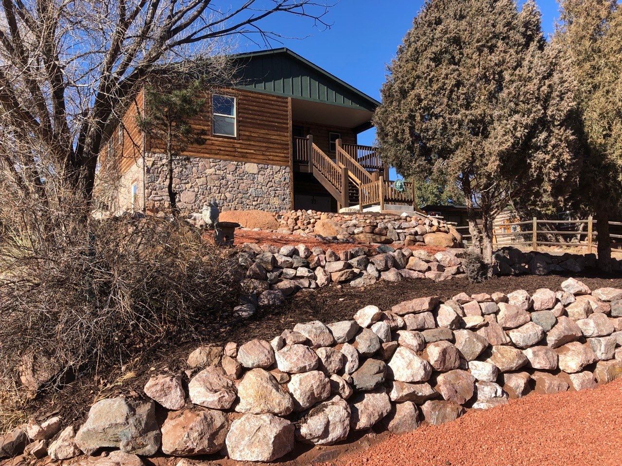 A house with stairs leading up to it is surrounded by trees and rocks.