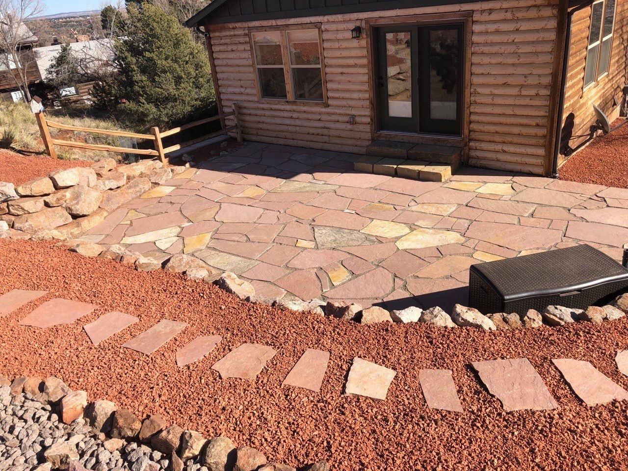 A log cabin with a stone patio in front of it
