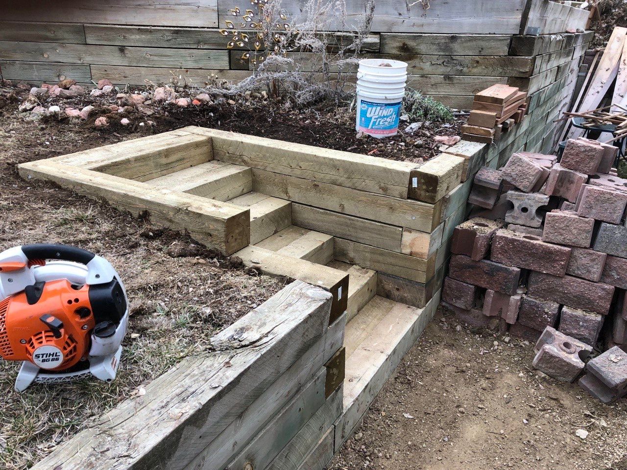 A chainsaw is sitting on the ground next to a wooden wall.