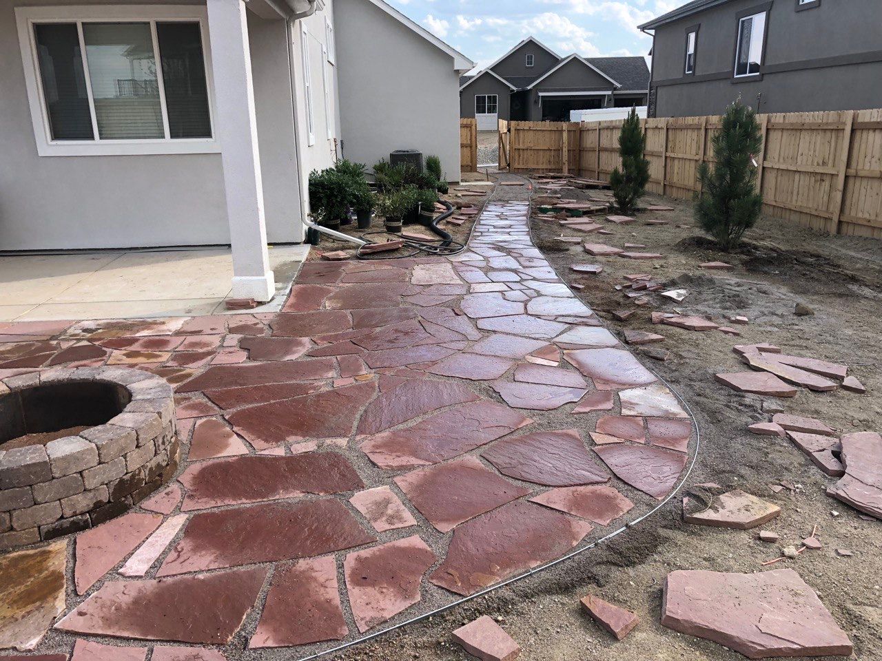 A stone walkway is being built in the backyard of a house.