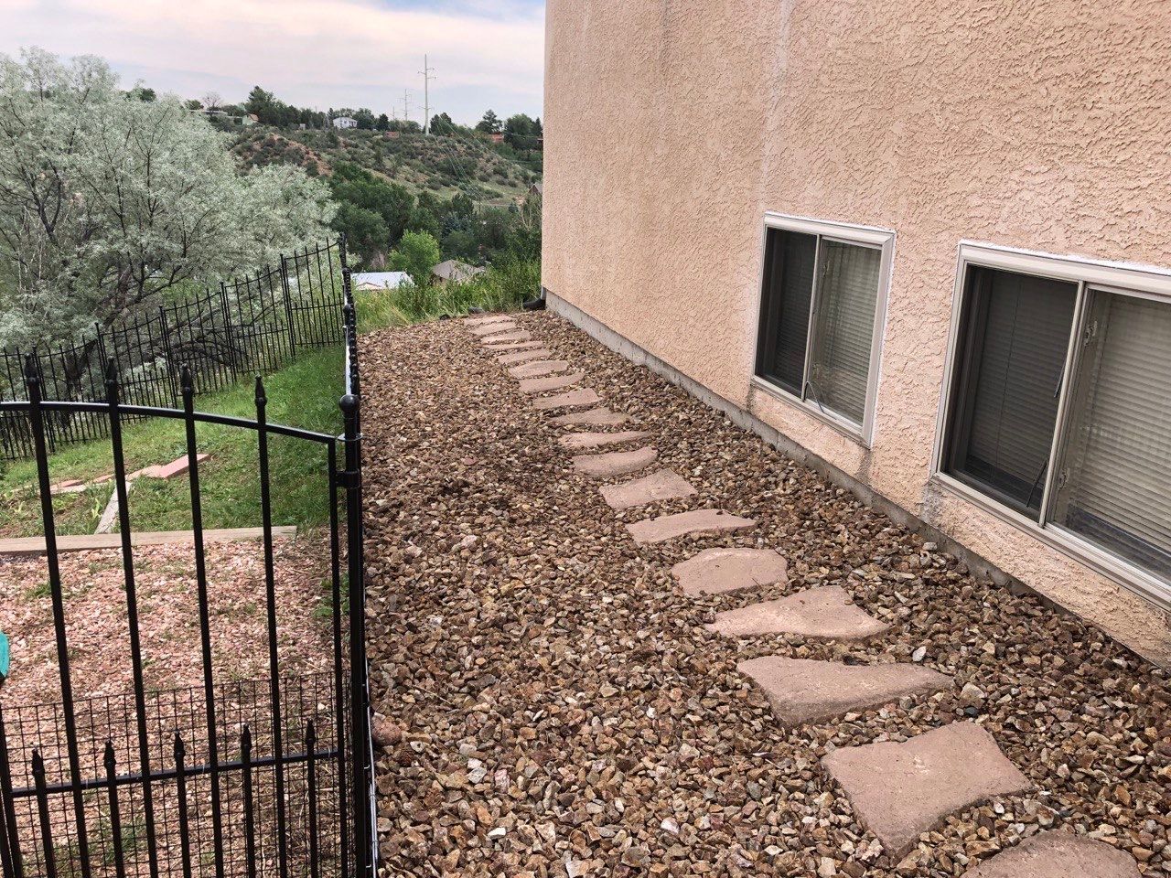 A stone walkway leading to a house with a fence and windows.
