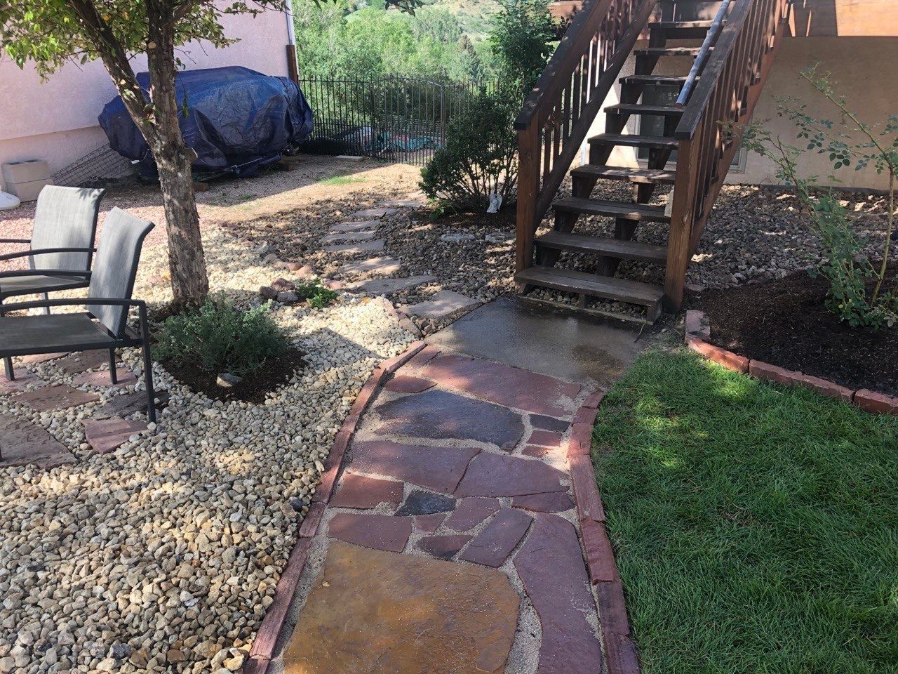 A stone walkway leads to a set of stairs in a backyard.