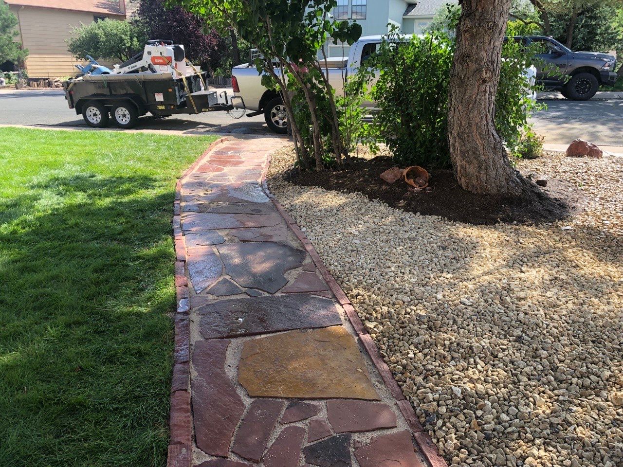 A truck is parked on the side of the road next to a stone walkway.