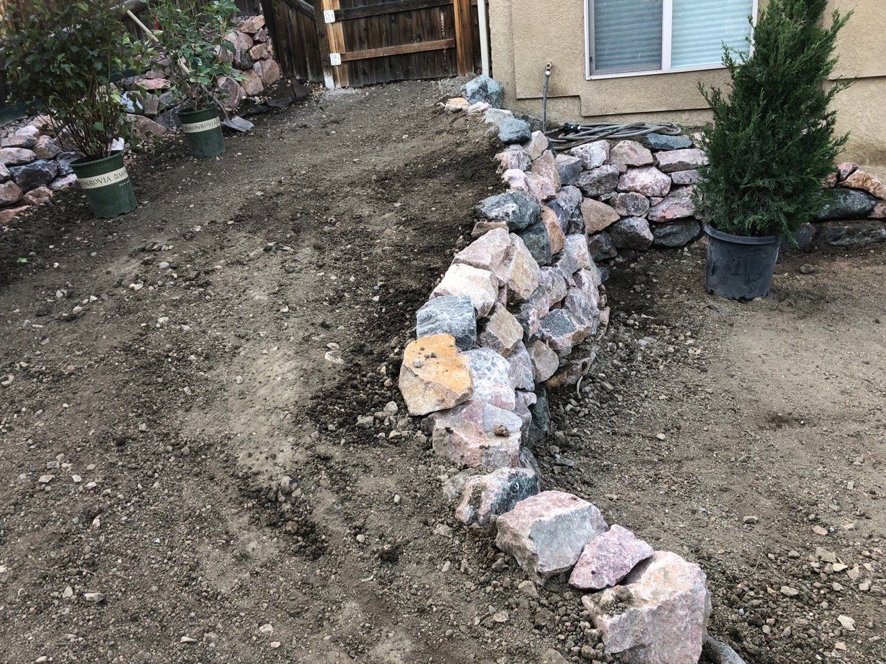 A stone wall is being built in front of a house.