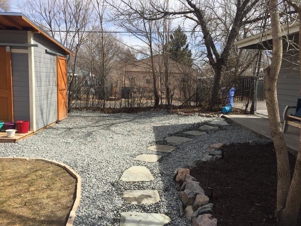 A gravel driveway with a shed in the background