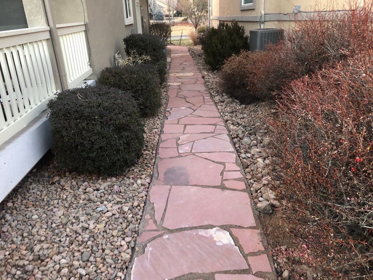 A stone walkway leading to a house with a white railing