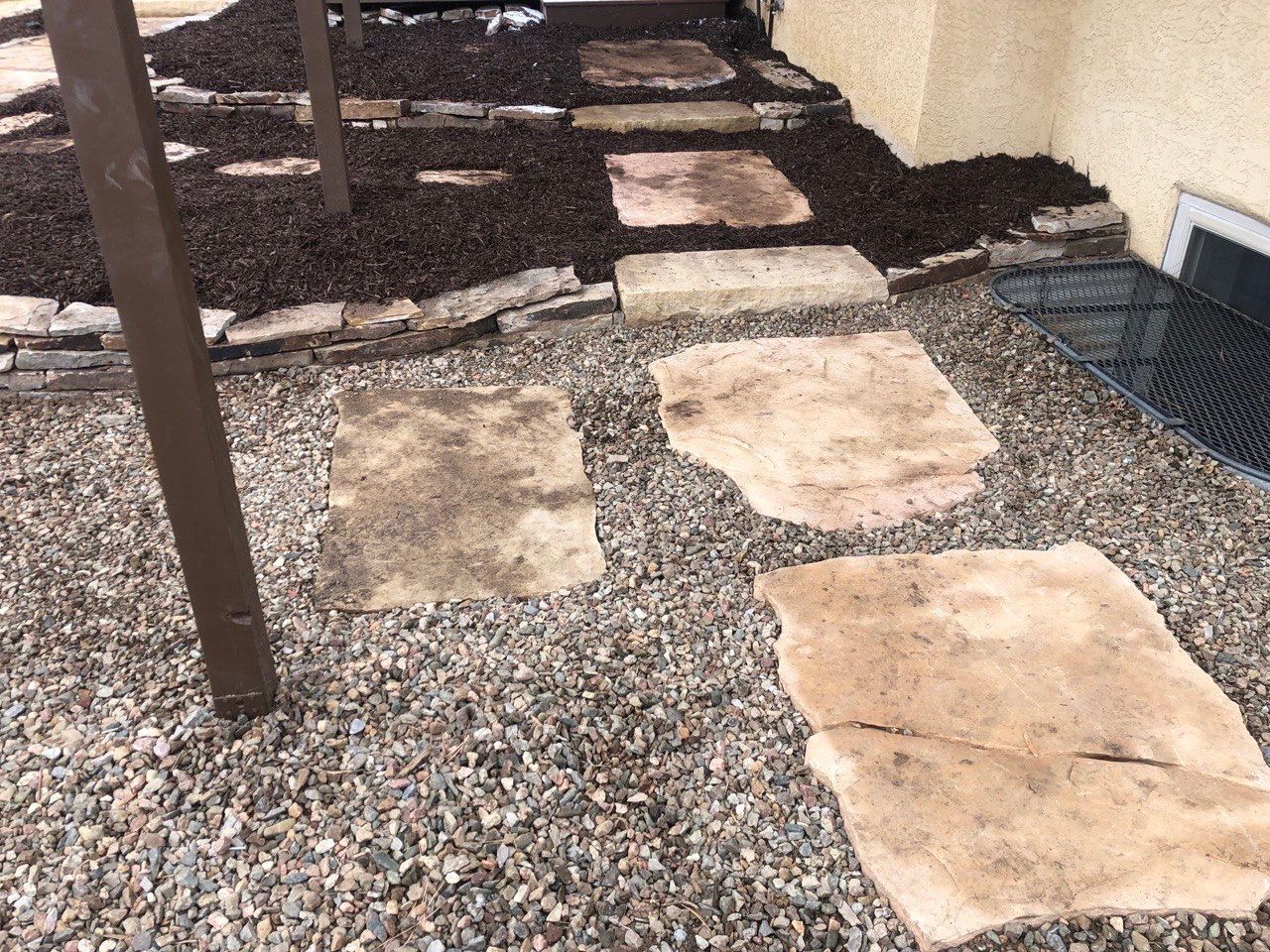 A walkway made of rocks and gravel next to a house.