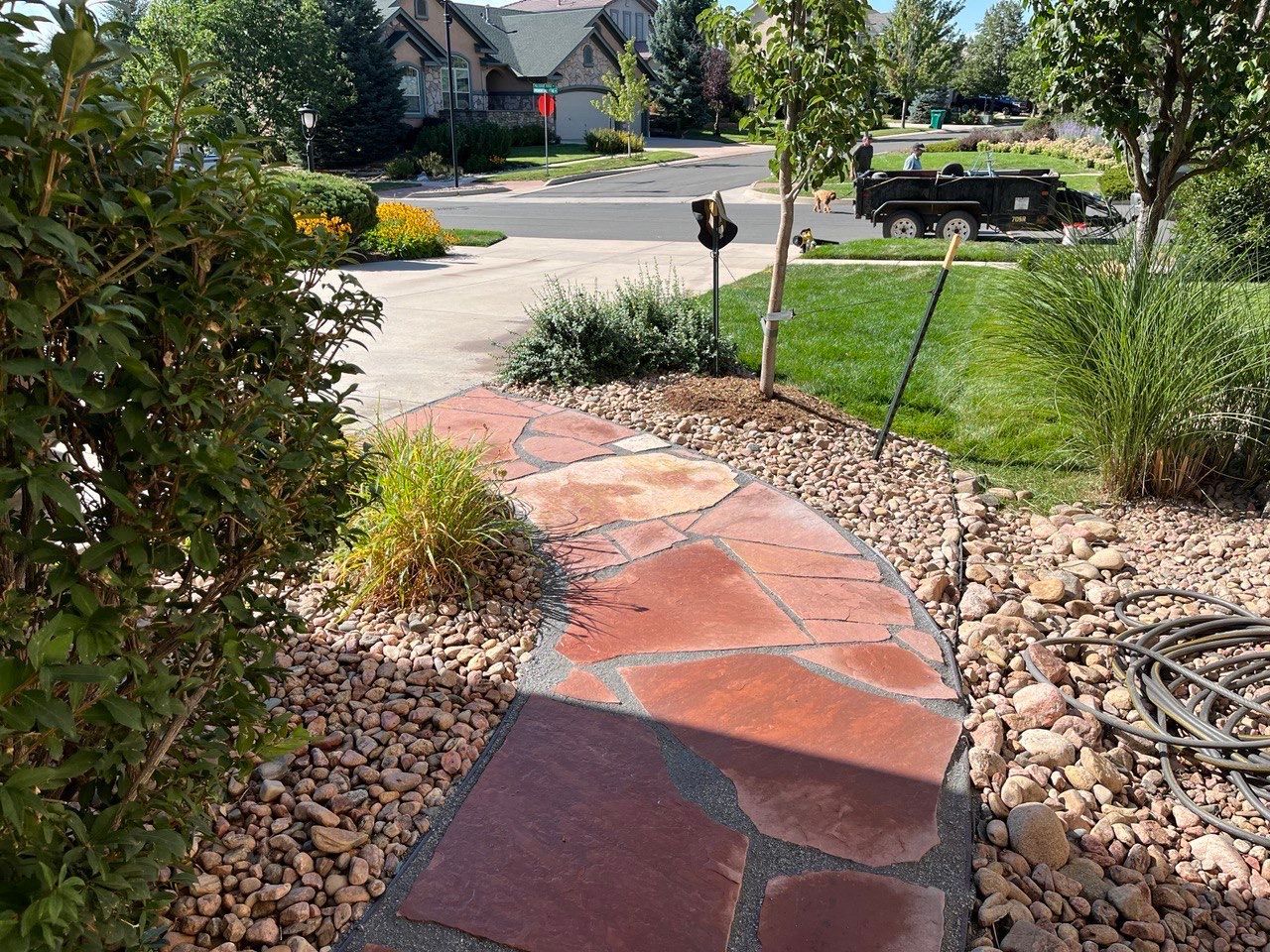 A stone walkway leads to a driveway in a residential neighborhood