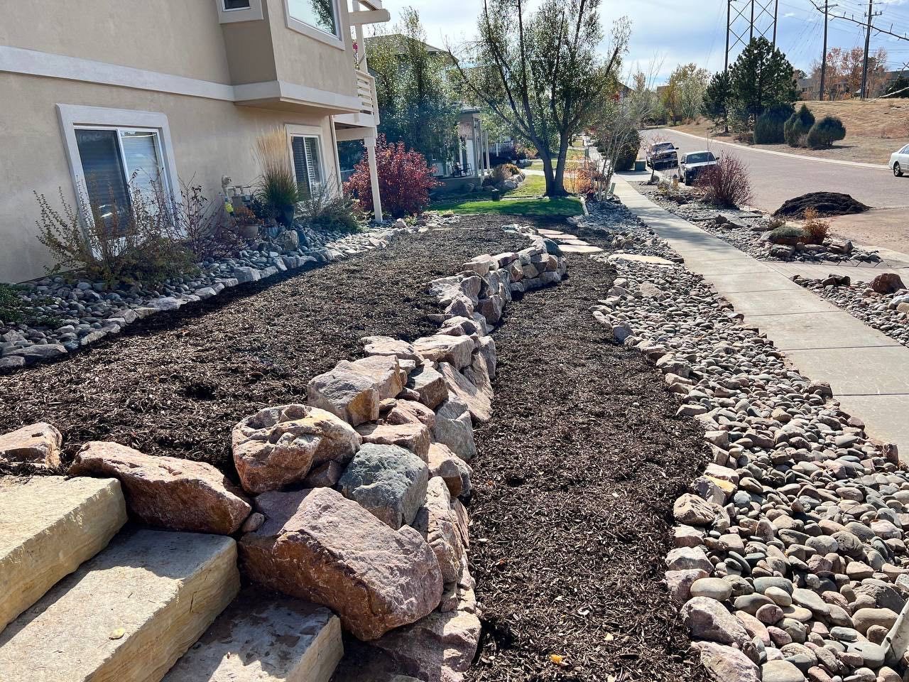 A large pile of rocks is in front of a house