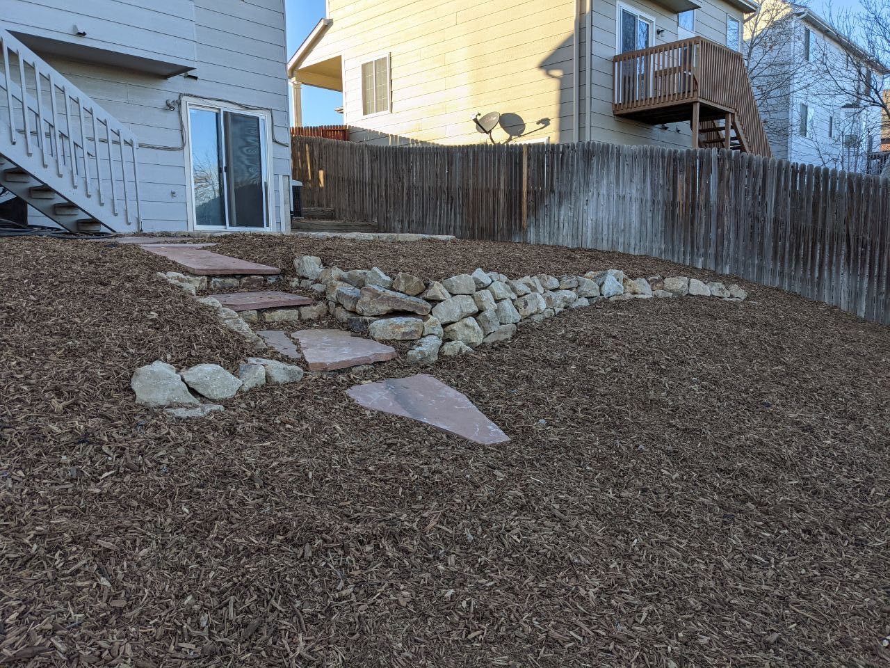 A house with stairs and a wooden fence behind it