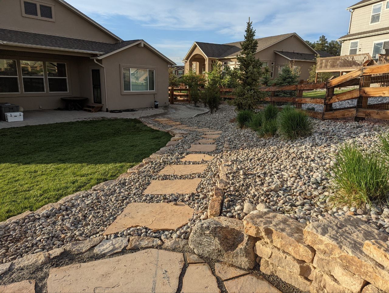 A stone walkway leading to a house with a wooden fence